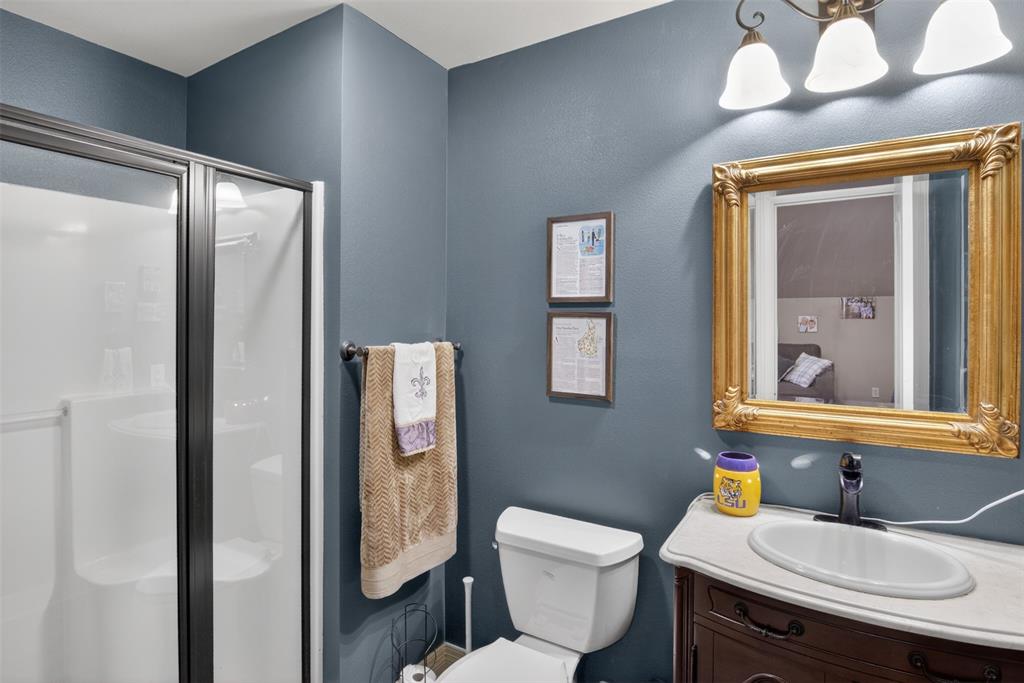 11868 Timber Ridge Drive Keithville, LA 71047 - Photo 23 of 37 Full bathroom featuring a shower enclosure with a dark-framed glass door, a vanity with a white countertop and oval sink, an ornate gold-framed mirror, and a three-light fixture with white bell shades