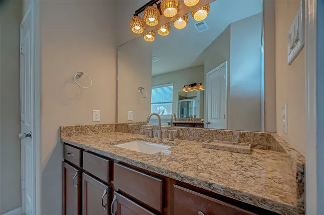 a bathroom with a granite countertop sink and a mirror