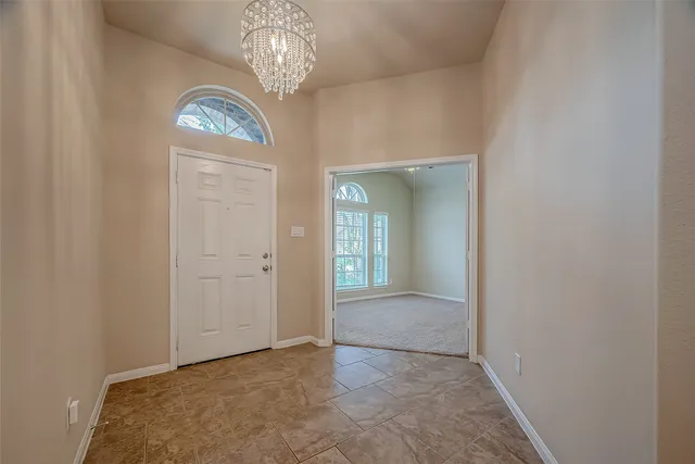 an empty room with a chandelier fan and windows