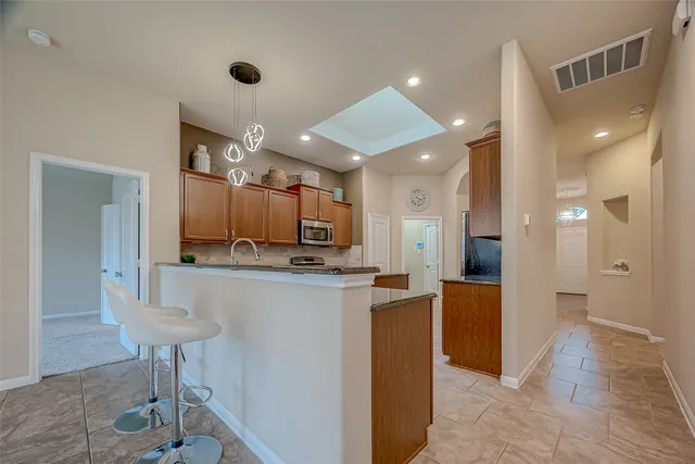 a open kitchen with stainless steel appliances kitchen island granite countertop a refrigerator and a sink