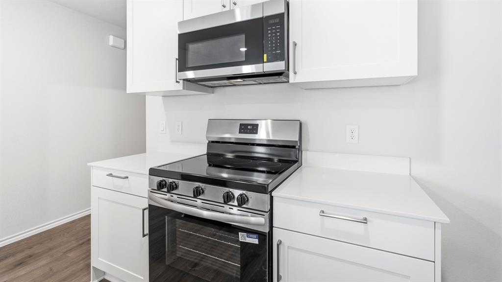 3519 Spring Time Street Forney, TX 75126 - Photo 25 of 37 Kitchen featuring white cabinetry, stainless steel microwave, stainless steel electric range, white countertops, and wood-finish flooring