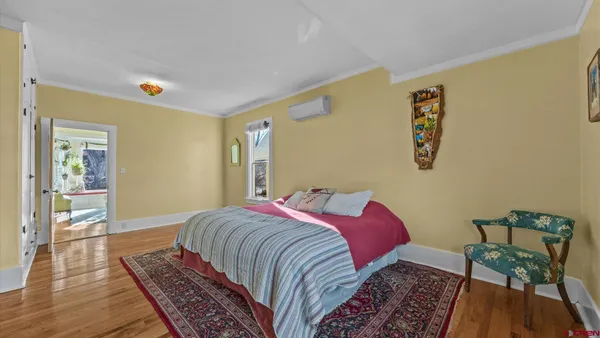 a spacious bedroom with a bed and wooden floor
