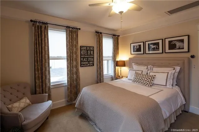 a bedroom with a large bed couch and windows