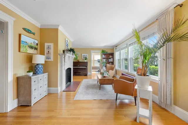 a living room with furniture a large window and wooden floor
