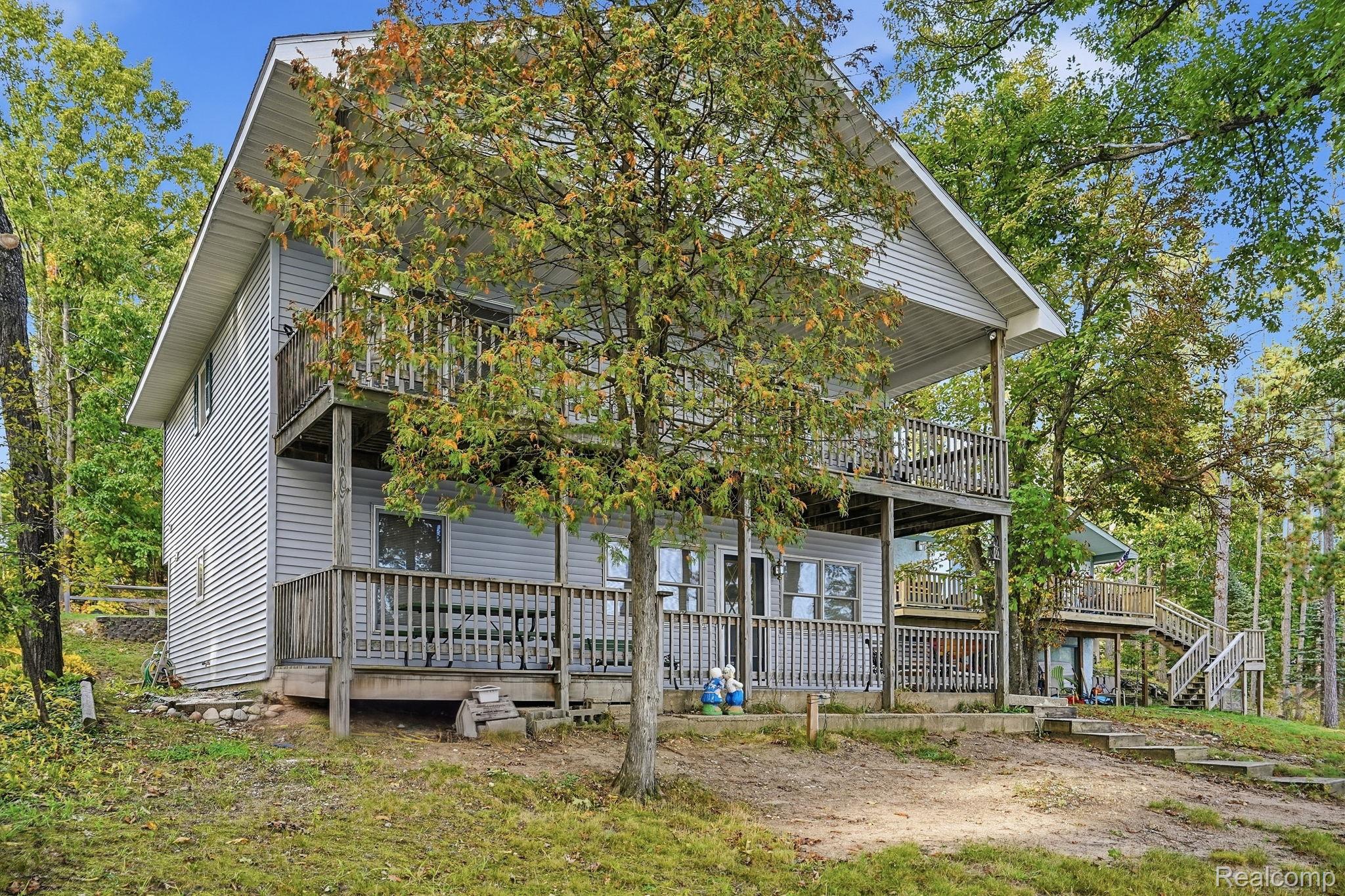 2259 Kassuba Road Gaylord, MI 49735 - Photo 5 of 46 Multi-level decking with wood railings, gray horizontal siding, and a prominent A-frame roofline