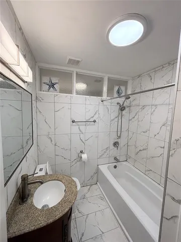 a bathroom with a granite countertop sink a toilet and bathtub