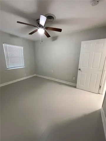 an empty room with chandelier fan and windows