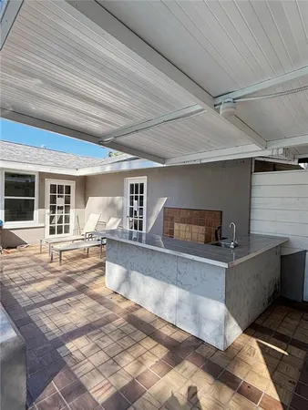 a view of a small house in front of a yard with potted plants
