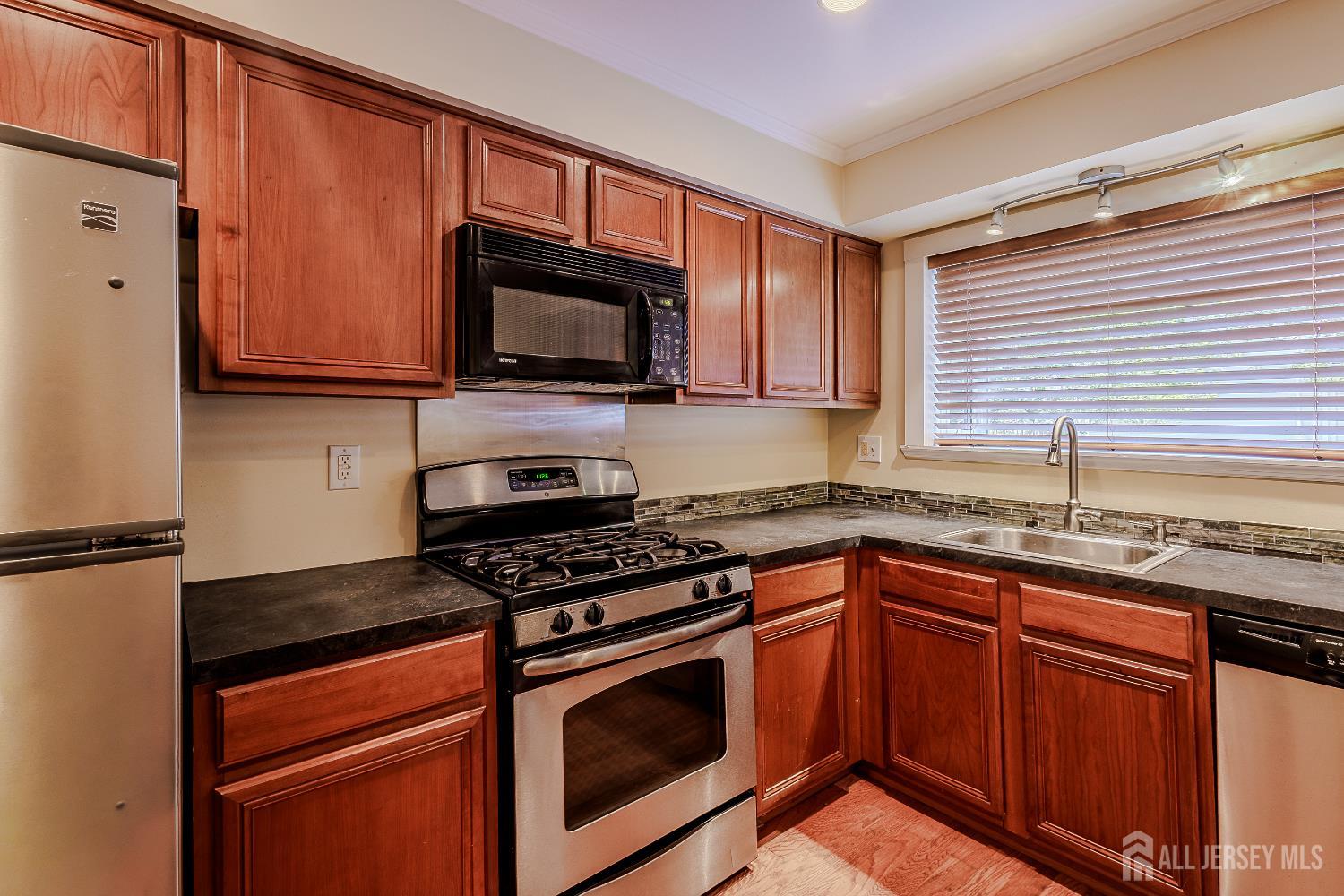412 Hawkshead Way Somerset, NJ 08873 - Photo 10 of 35 a kitchen with granite countertop wooden cabinets stainless steel appliances and a window