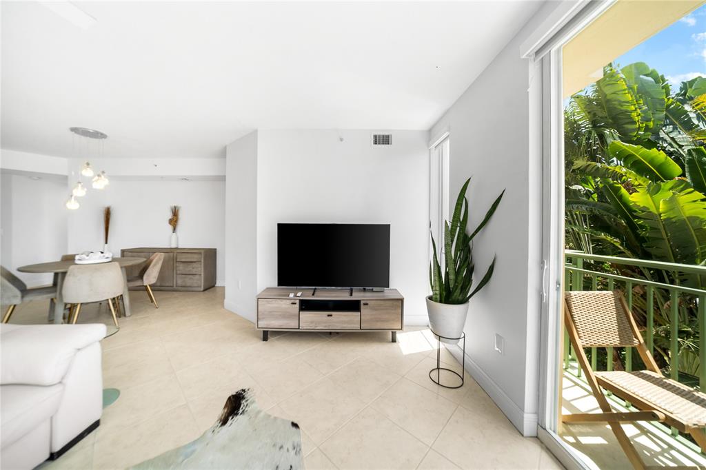 3210 Northeast 5th Street, Unit 203 Pompano Beach, FL 33062 - Photo 31 of 61 a living room with furniture a potted plant and a flat screen tv