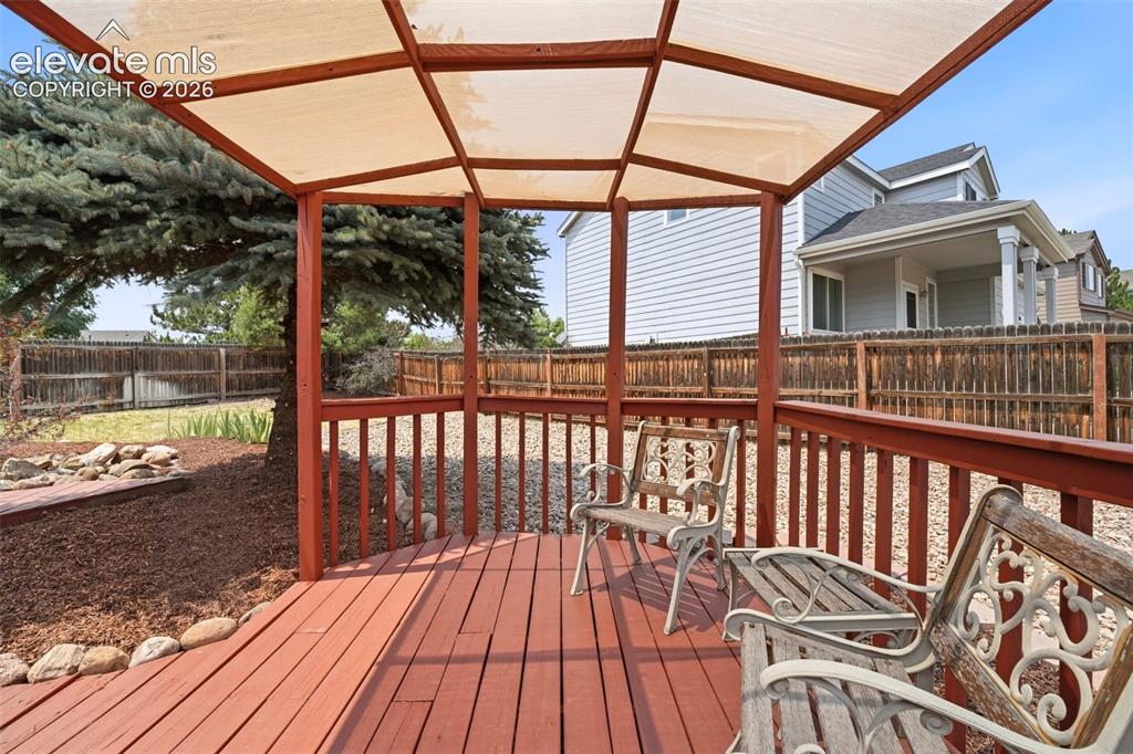 7904 Coffee Road Peyton, CO 80831 - Photo 37 of 48 Expansive wooden deck featuring a built-in pergola with a fabric canopy