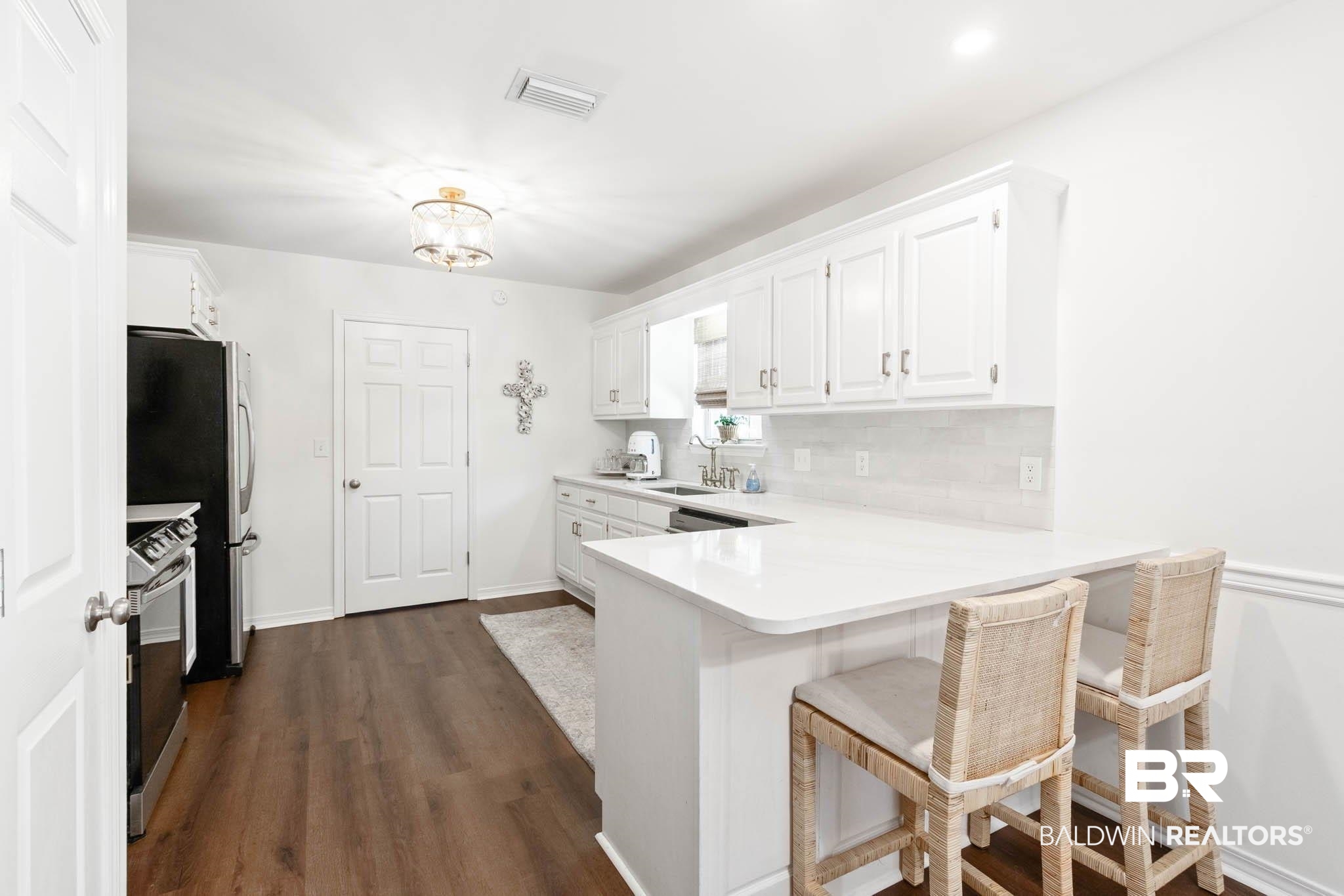 20685 Lowry Drive Fairhope, AL 36532 - Photo 20 of 48 Kitchen featuring a peninsula, white cabinetry, a kitchen breakfast bar, backsplash, and dark wood-type flooring