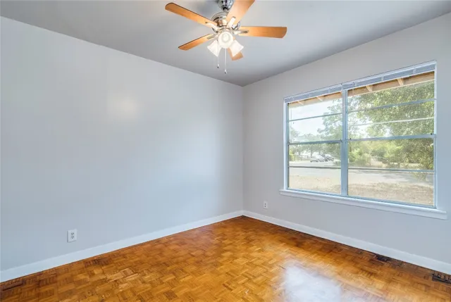 an empty room with a window and a fan