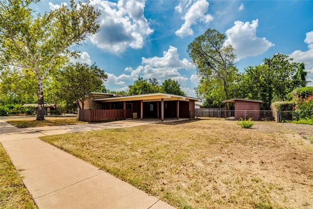 a view of backyard with wooden fence and a large tree