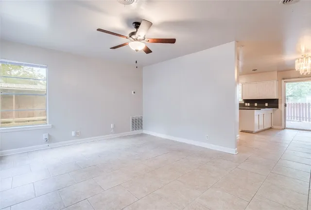 an empty room with windows and ceiling fan