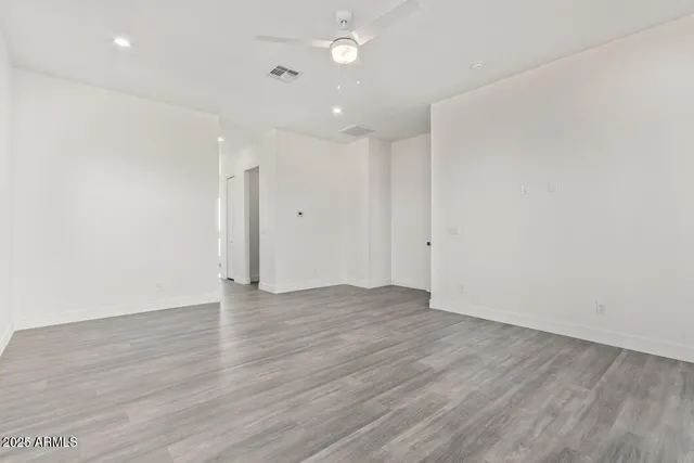an empty room with wooden floor and natural light