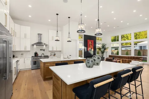 a kitchen with stainless steel appliances granite countertop a stove a refrigerator a kitchen island a sink and chairs