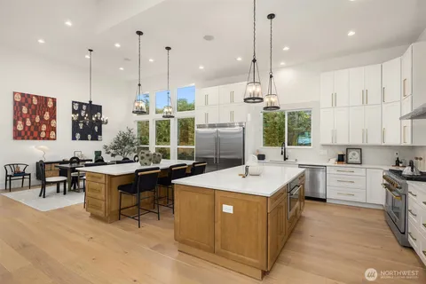 a large kitchen with kitchen island a sink a stove a center island a dining table and chairs