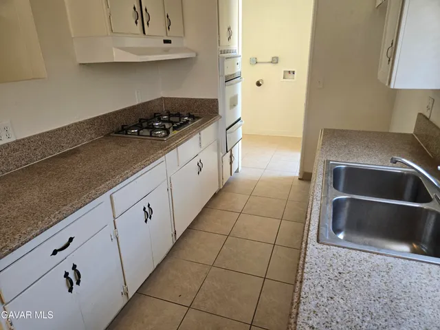 a kitchen with granite countertop a sink a stove and cabinets