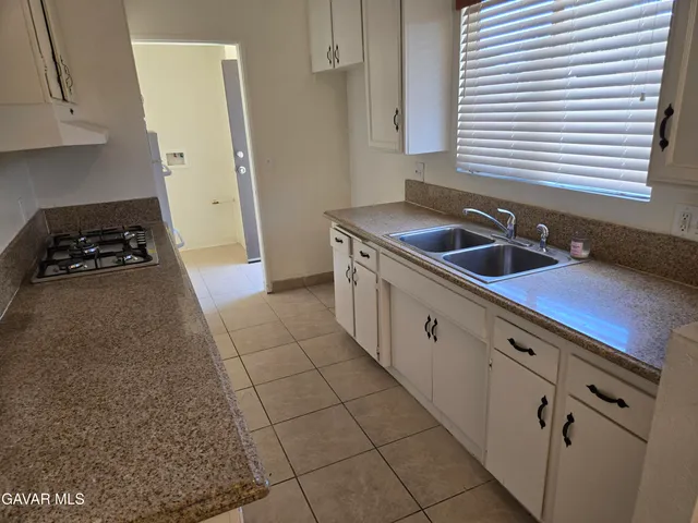 a kitchen with granite countertop a stove a sink and a refrigerator
