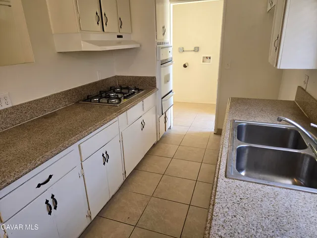 a kitchen with granite countertop a sink a stove and cabinets