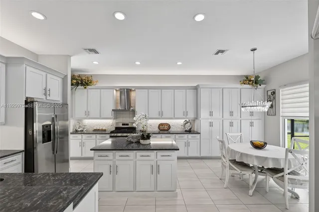 a kitchen with stainless steel appliances kitchen island granite countertop a sink refrigerator and cabinets