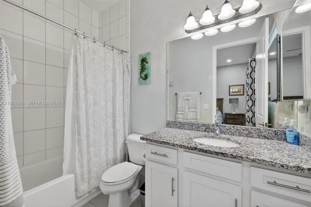 a bathroom with a granite countertop sink a toilet and a mirror
