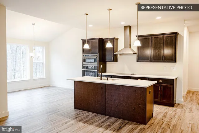 a kitchen with stainless steel appliances granite countertop a sink a stove and a wooden floors