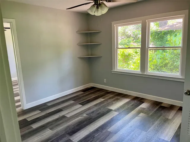 a view of empty room with wooden floor and fan