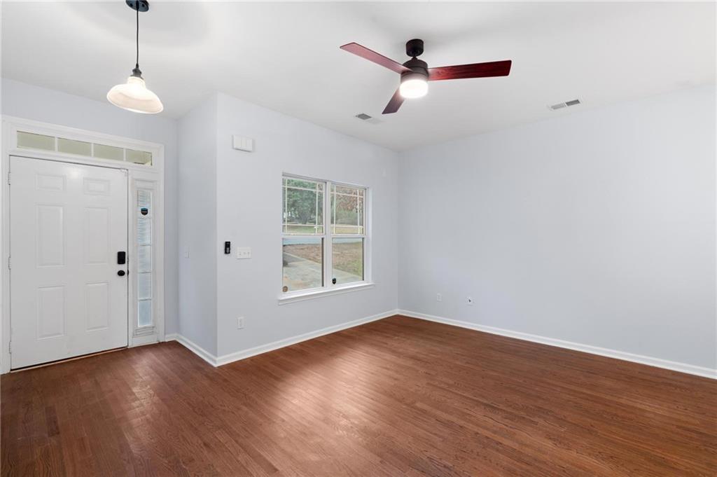 49 Harlan Road Southwest Atlanta, GA 30311 - Photo 4 of 38 an empty room with wooden floor ceiling fan and windows