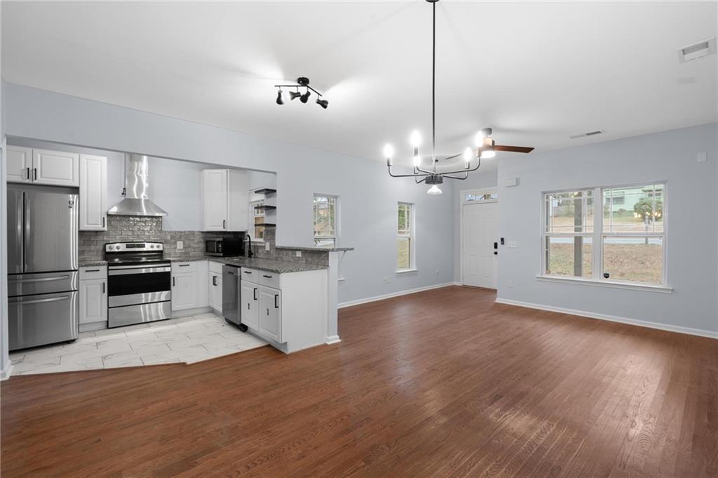 49 Harlan Road Southwest Atlanta, GA 30311 - Photo 7 of 38 a kitchen with stainless steel appliances granite countertop a refrigerator a sink dishwasher a stove and white cabinets with wooden floor