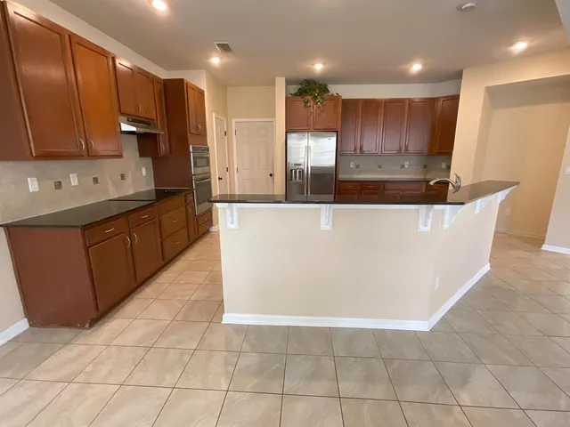 a large kitchen with stainless steel appliances granite countertop a large counter top and wooden cabinets