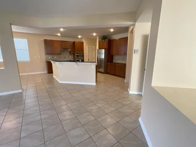 a view of kitchen with kitchen island granite countertop a sink and a stove top oven