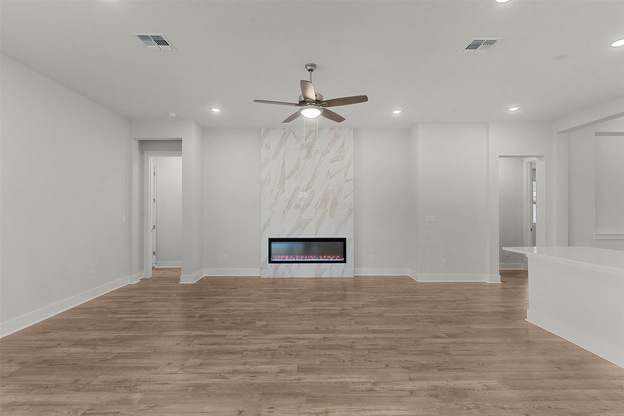 1129 Pansy Trail Georgetown, TX 78628 - Photo 15 of 29 Living area featuring wood-finish flooring, a contemporary electric fireplace with a marble-look surround, a ceiling fan, and recessed lighting