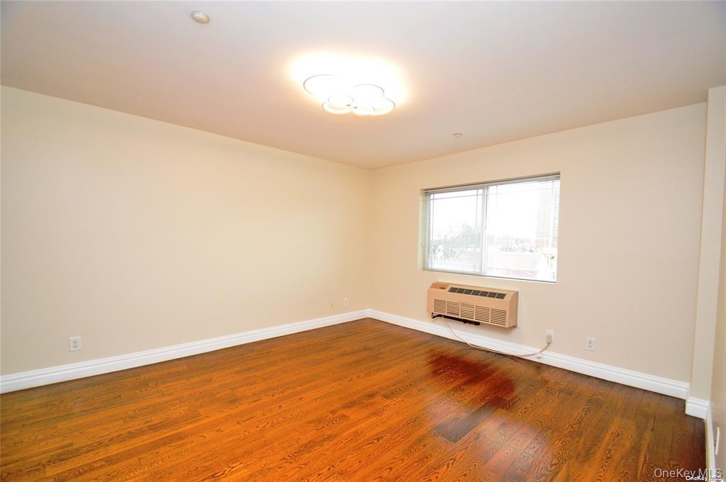 69-14 41st Avenue, Unit 401 Queens, NY 11377 - Photo 10 of 19 an empty room with wooden floor and windows