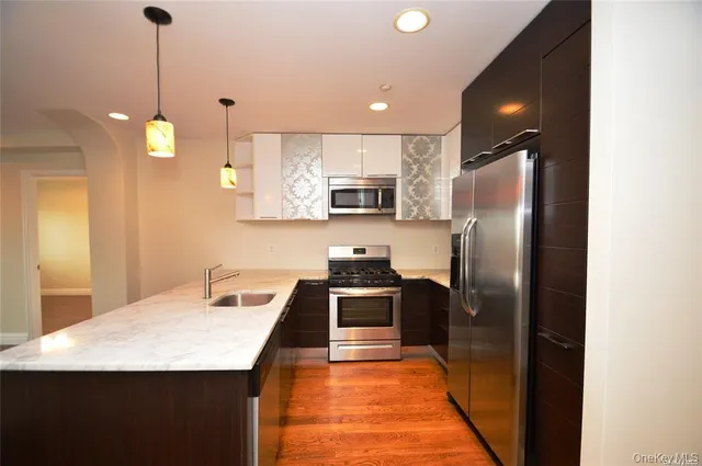 a kitchen with kitchen island a sink stainless steel appliances and wooden floor