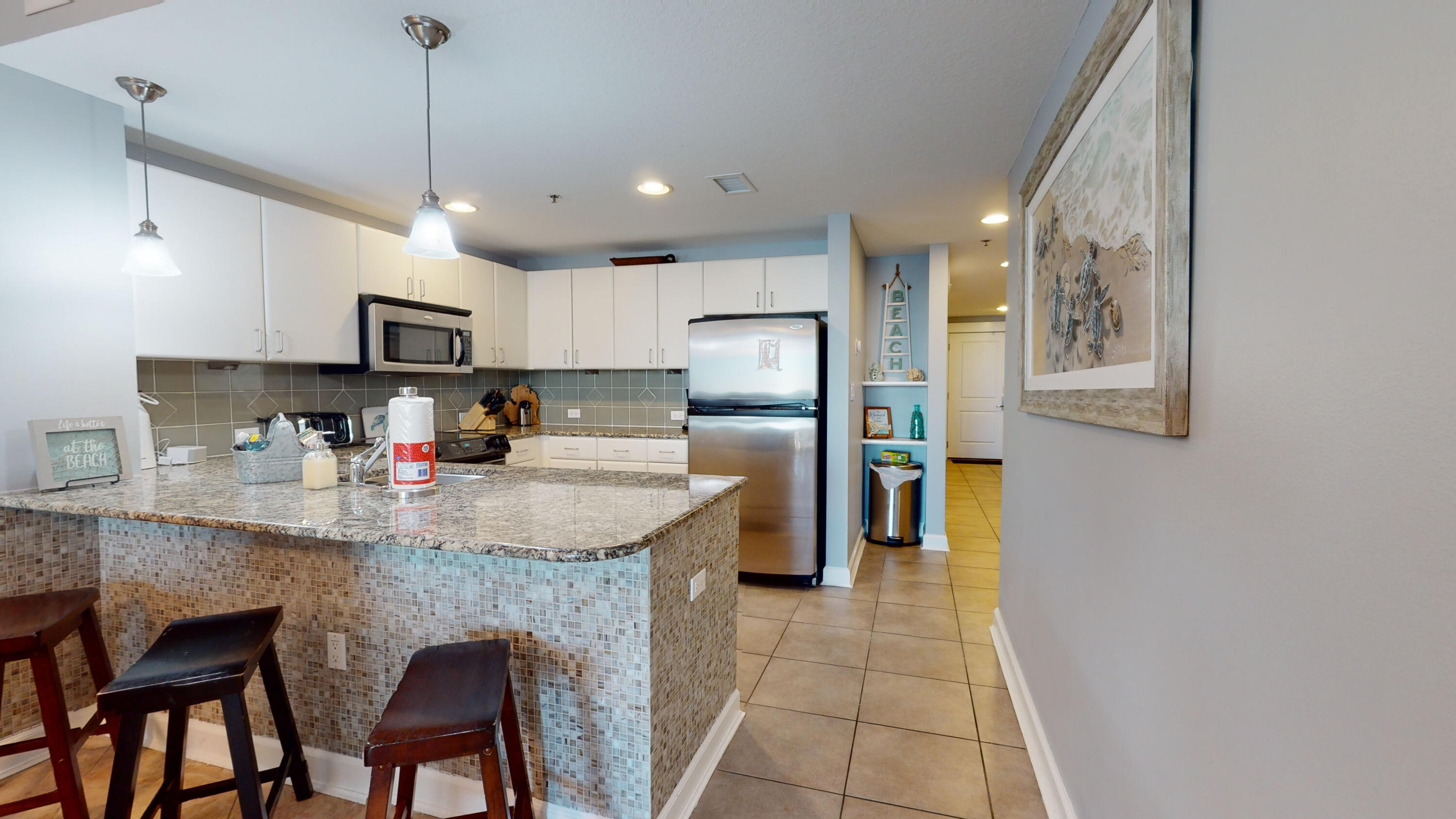 11807 Front Beach Road, Unit 1402 Panama City Beach, FL 32407 - Photo 16 of 37 a kitchen with stainless steel appliances granite countertop a sink a refrigerator and a stove