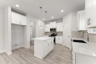 a kitchen with kitchen island a sink stainless steel appliances and white cabinets