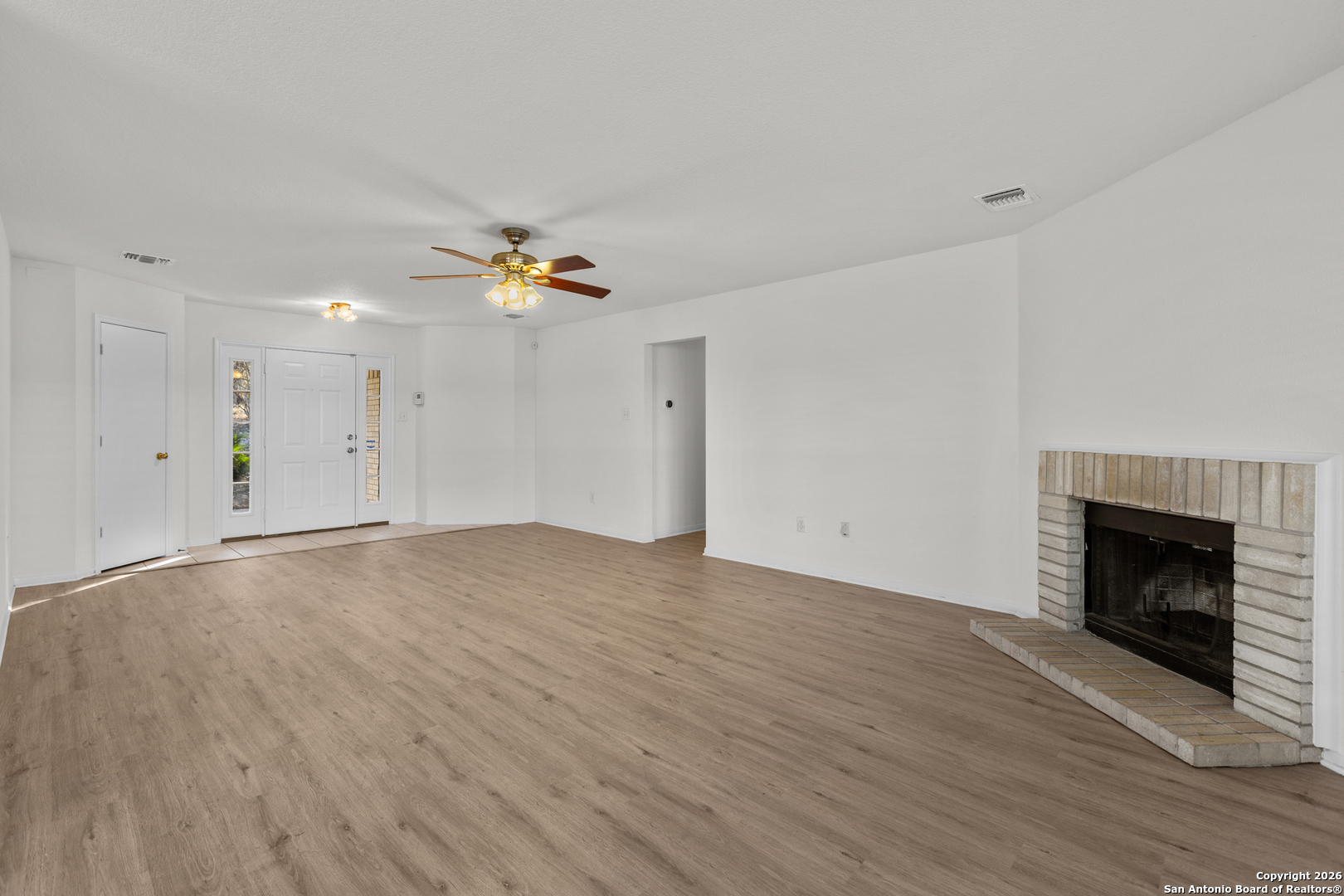 431 Windy Hill Drive Spring Branch, TX 78070 - Photo 11 of 45 an empty room with wooden floor fireplace and windows