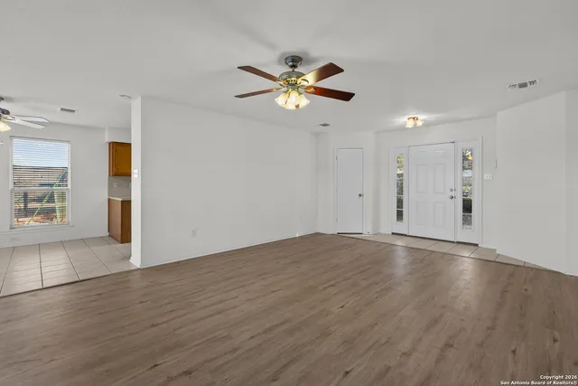 a view of an empty room with window and wooden floor