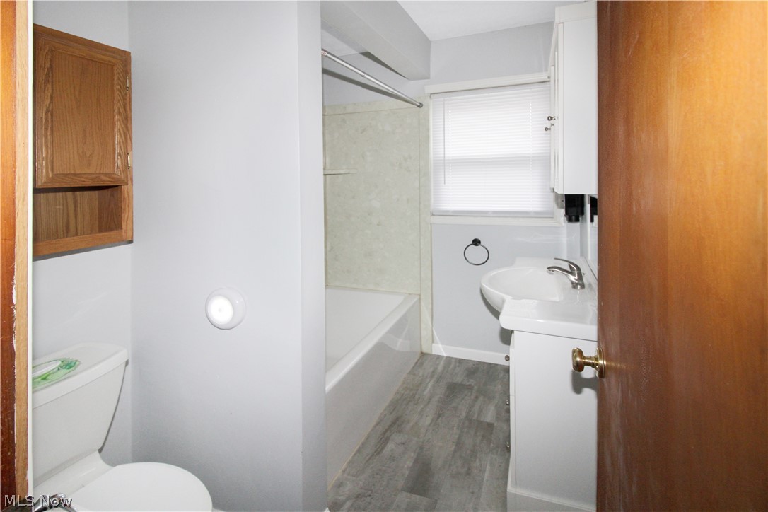 1036 West Fremont Road Port Clinton, OH 43452 - Photo 20 of 32 Full bathroom featuring shower / tub combination, wood-type flooring, toilet, and vanity