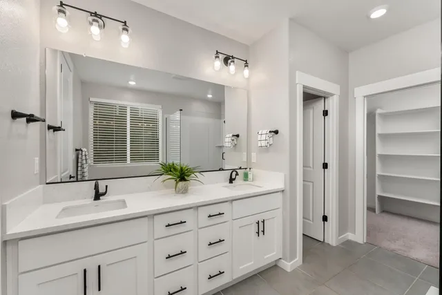 a bathroom with a double vanity sink mirror and next to a window