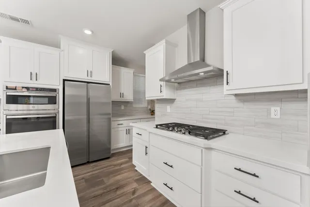 a kitchen with stainless steel appliances granite countertop a stove a refrigerator and a white cabinets
