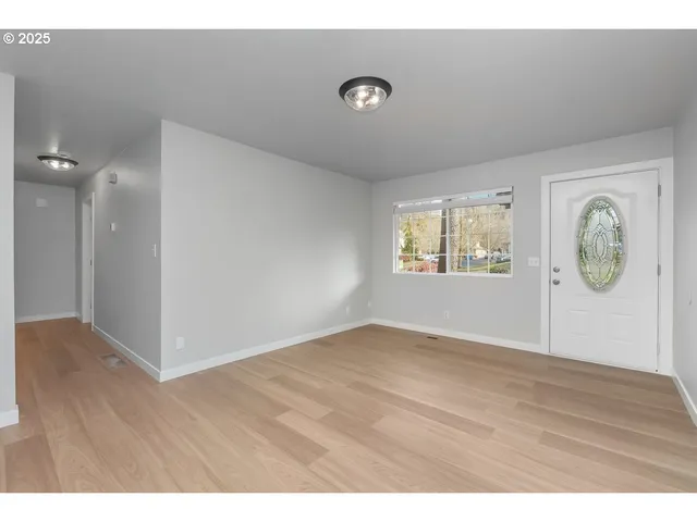 a view of an empty room with window and wooden floor