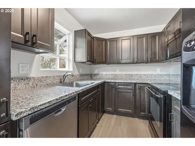 a kitchen with granite countertop a sink stainless steel appliances and cabinets