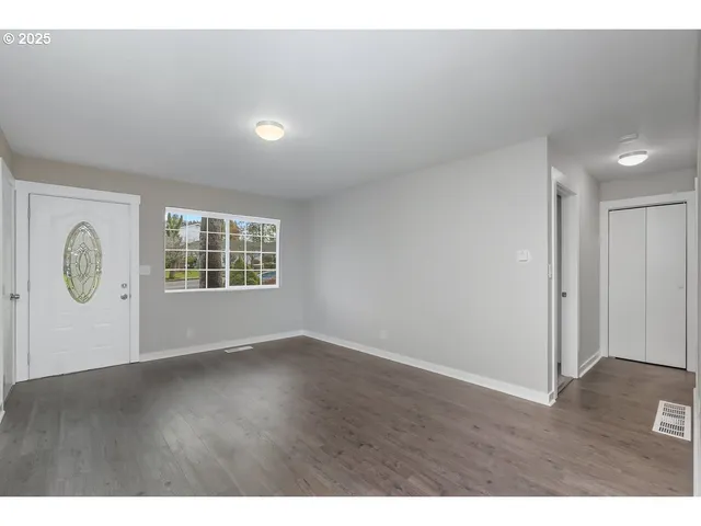 a view of an empty room with wooden floor and windows