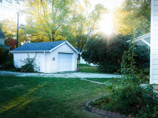 a view of a yard in front of a house with plants and large trees