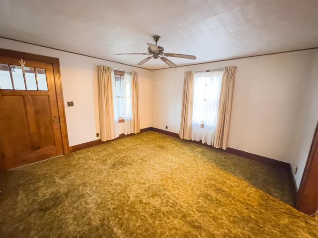 an empty room with windows and fan