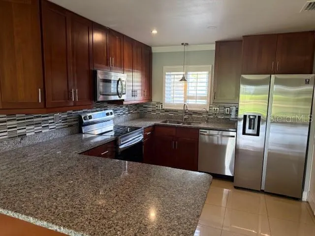 a kitchen with stainless steel appliances granite countertop a sink a stove and a refrigerator