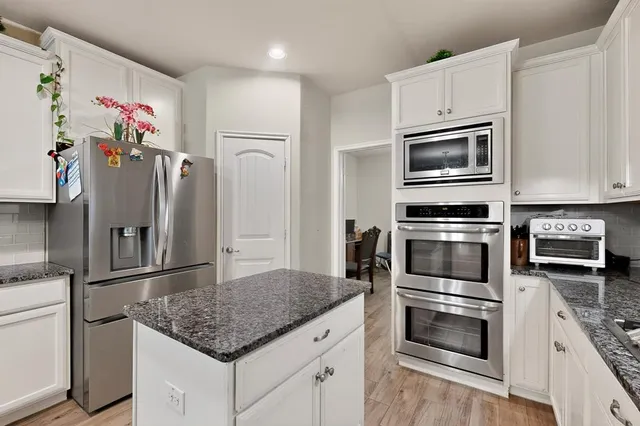 a kitchen with granite countertop a refrigerator oven and stainless steel appliances